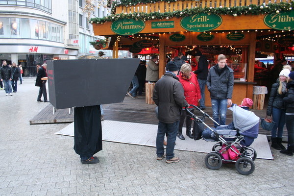 [Foto: Menschliche Kamera vor Pommes-Bude]