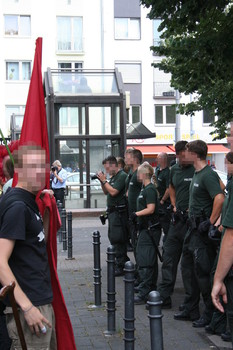 [Foto: Polizei-Fotograf und weitere Polizisten vor Demonstranten]