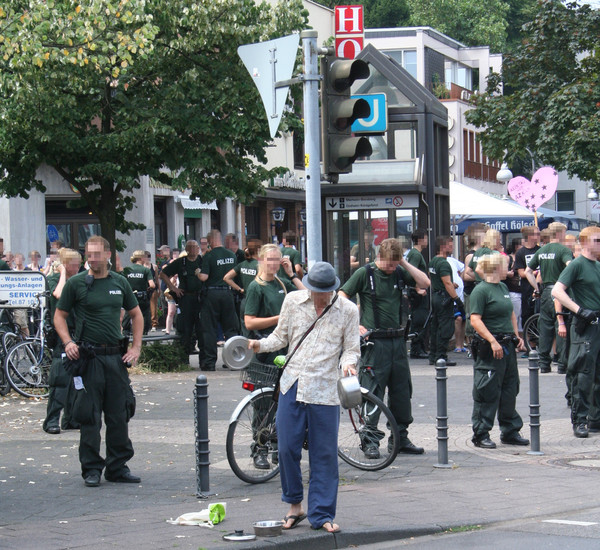 [Foto: Polizei und Mann mit Kochtopf]