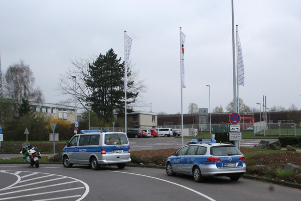 [Foto: Polizei-Fahrzeuge vor BfV-Fahnen]