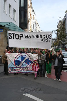 [Foto: Stop-Watching-Us-Front-Banner am Kopf des Demozugs. Kleines Mdchen luft davor.]