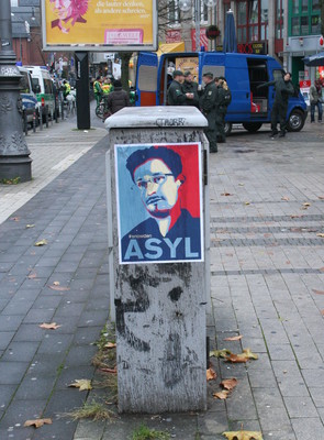 [Foto: Asyl-fr-Snowden-Plakat mit Polizei im Hintergrund]