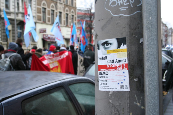 [Foto: Freiheit-statt-Angst-Aufkleber mit Demonstranten im Hintergrund]