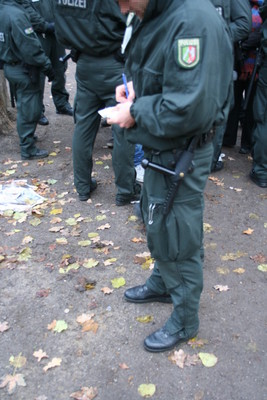 [Foto: Polizist notiert Personalien von Ausweis]