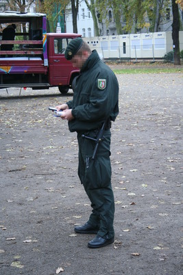 [Foto: Polizist mit Mobiltelefon und Ausweis]