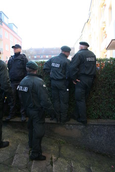 [Foto: Polizisten spingsen ber Hecke]