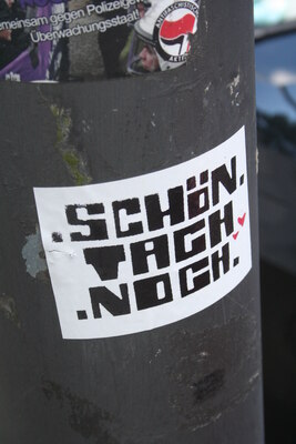 [Foto: 'Schön Tach noch' und weiterer Aufkleber]