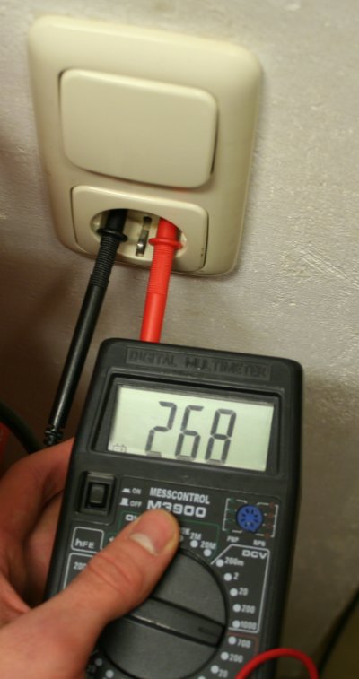 [Foto: Hand mit Multimeter dessen Kabel in einer Steckdose stecken. Es lieg eine Wechselspannung von
     268 Volt an]