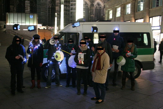 [Foto: Gruppenfoto mit Kamera-Laternen vor Polizeibus und Klner Dom]