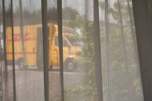 [Foto eines Postwagens, aufgenommen durch einen Vorhang hindurch]