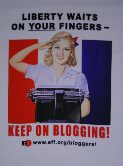 [Foto: Aufdruck des ersten T-Shirts. Blondine hinter einer Schreibmaschine. berschrift
     ist 'Liberty waits on your fingers'; Unterschrift ist 'Keep on Blogging!']