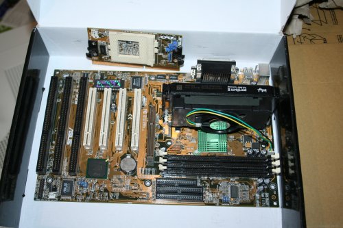 [Foto: Mainboard Asus P2B mit eingestecktem Prozessor und einem losen Sockel-370-Adapter]